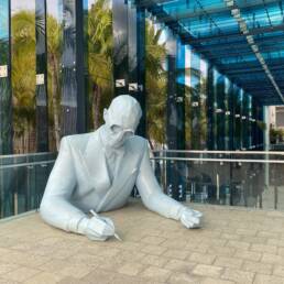 large blue sculpture of man writing